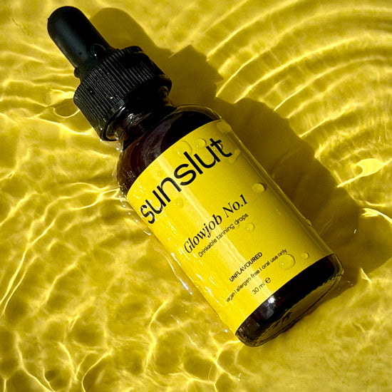 Sunslut Glowjob No.1 drinkable tanning drops — amber bottle with yellow label on glowing water surface.