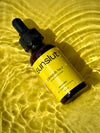 Sunslut Glowjob No.1 drinkable tanning drops — amber bottle with yellow label on glowing water surface.